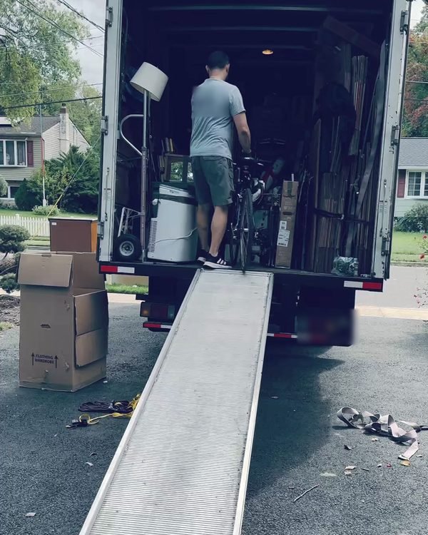 A mover rolling a bicycle up the ramp into our truck in a suburban driveway
