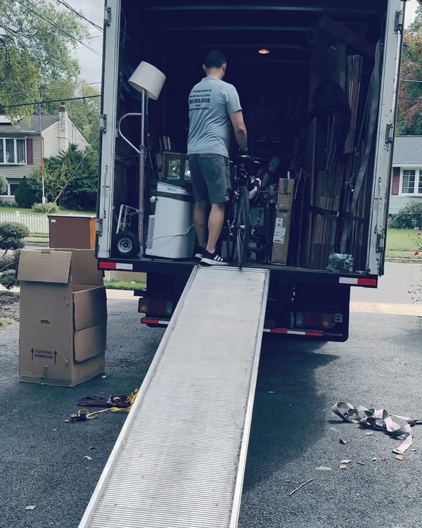 A mover rolling a bicycle up the ramp into our truck in a suburban driveway
