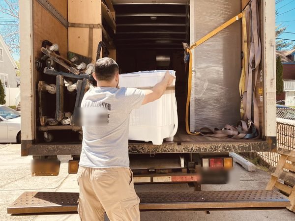 A mover lifting a washer onto our truck, straps and dollies inside